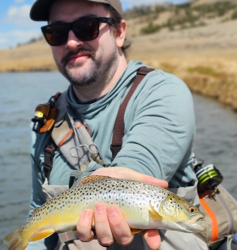 James holding a trout while fly fishing on a river