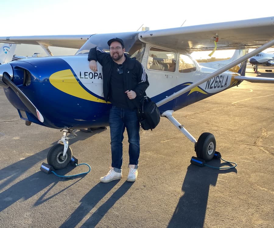 James standing in front of a small plane on the tarmac